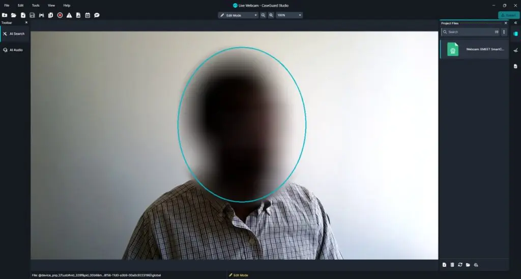 Video call screenshot showing a person with a blurred face inside a cyan circular outline around the head in a dark video chat interface with a plaid shirt.