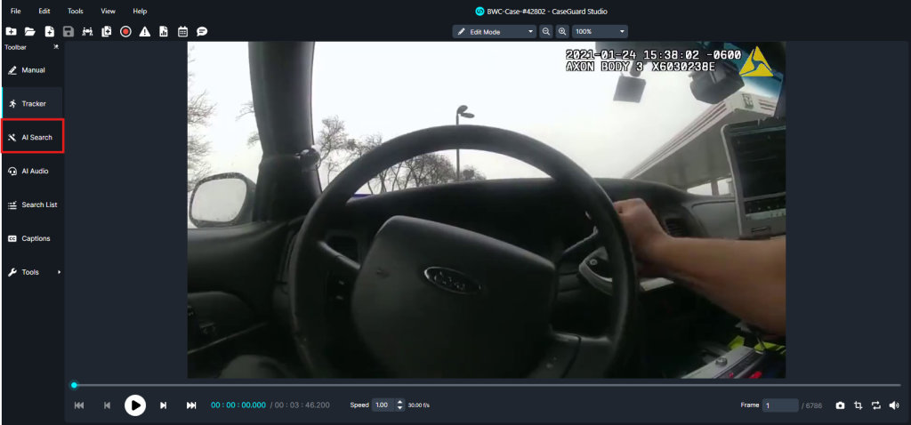 Front-seat view from a car dashboard camera showing a driver’s hand on the steering wheel and the windshield ahead; police body‑cam overlay and equipment visible on the dashboard.