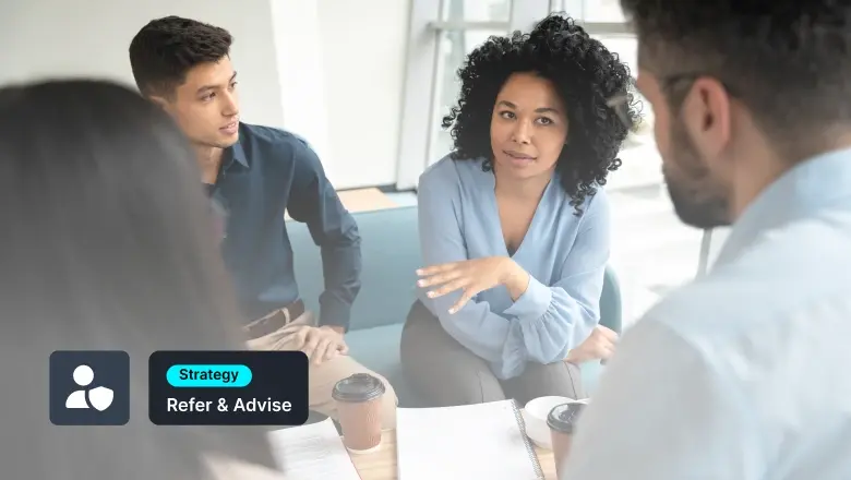 A diverse group of colleagues in a meeting, woman speaking while others listen, with notes and coffee on the table and a badge reading 'Strategy' and 'Refer & Advise' in the corner.